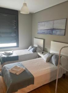 1 dormitorio con 2 camas y ventana en TORRES DE MONTENUÑO, en Oviedo