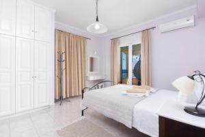 a white bedroom with a bed and a window at Villa Spyros in Nisaki +41 photos