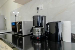 a kitchen counter with a coffee maker and a microwave at New Luxury Apartment close to State House Nairobi in Nairobi