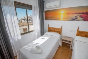 a hotel room with two beds and a window at Apartments Niko in Santa Eularia des Riu