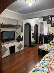 a room with a bed and a tv on a wall at HOSTEL FAMILIA ZANATTA in Caxias do Sul