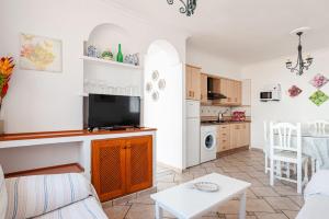 a living room with a tv and a kitchen at Chalet Fuente1 piscina común famila in Conil de la Frontera