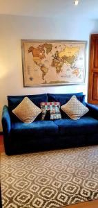 eine blaue Couch mit zwei Kissen und eine Karte an der Wand in der Unterkunft Cantinho do Auka - Studio in Aveiro