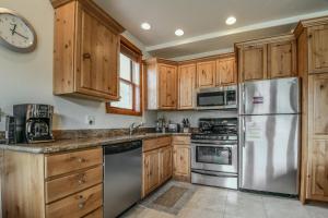 una cocina con armarios de madera y electrodomésticos de acero inoxidable en Antlers Gulch 501, en Keystone