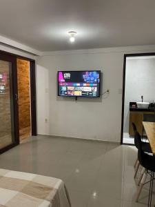 un salon avec une télévision au mur dans l'établissement Sezimbra village flat, à Natal