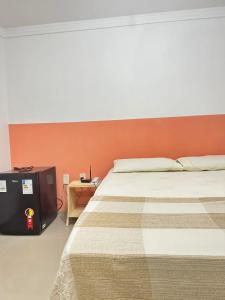 une chambre avec un grand lit avec un mur orange dans l'établissement Sezimbra village flat, à Natal