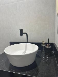 une baignoire blanche sur un comptoir noir dans une salle de bain dans l'établissement Sezimbra village flat, à Natal 2 autres photos