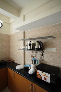 a kitchen with a counter with a coffee maker and a microwave at Castle Suites by Haven Homes, Kempegowda International Airport road in Bangalore