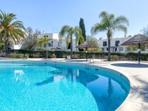 een zwembad met palmbomen en parasols bij Lovely Apartment in Albufeira 2BD 250m Beach Ocean view and AC Wi-Fi Pool in Albufeira