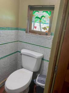 a bathroom with a white toilet and a window at 'Crows Nest' Studio Apt. in Big Corn Island