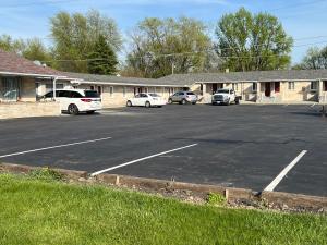 Un estacionamiento con autos estacionados frente a un edificio. en Bestway Inn, en Muncie