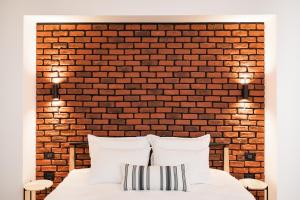 uma parede de tijolos atrás de uma cama com duas almofadas brancas em ComFee Apartment - Ultracentral em Brasov