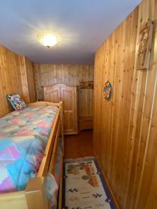 1 dormitorio con 1 cama y paredes de madera en Appartamento Cerreto Laghi, en Cerreto Laghi