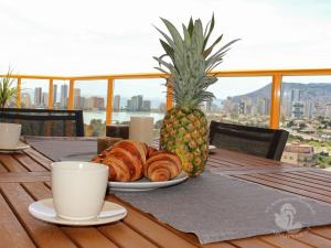 einen Tisch mit einem Teller Croissants und einer Ananas in der Unterkunft Flamenco Ambar Luxury Apartment 15 Planta in Calpe