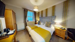 Cette chambre comprend un grand lit et une fenêtre. dans l'établissement Tynedale Hotel, à Llandudno