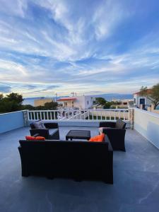 a patio with couches and tables on a balcony at Nikoli House with Jacuzzi in Vaia +6 photos