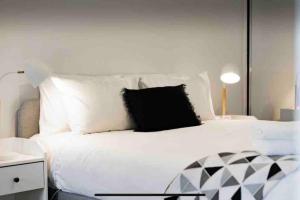 a bedroom with a white bed with black pillows at 1Br Braddon retreat with mountain views in Canberra +11 photos