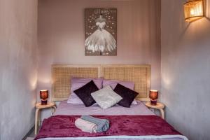 Cette chambre comprend un lit avec deux lampes et une robe sur le mur. dans l'établissement Cottage Au Coin du Feu, à Rambouillet