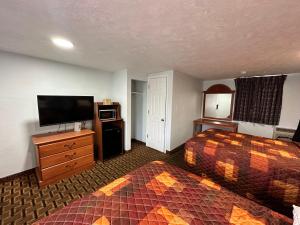 a hotel room with two beds and a flat screen tv at Bestway Inn in Muncie