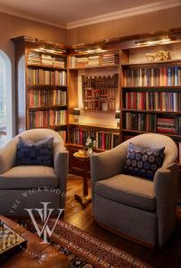 een woonkamer met 2 stoelen en boekenplanken bij Wickwood Inn in Saugatuck