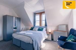 a bedroom with a bed and a blue chair at Stylish Central Eden Cottage with Courtyard & Free Parking in Dundee