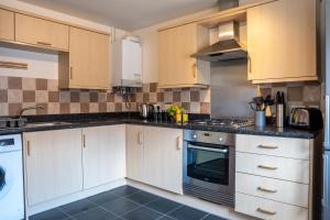 a kitchen with white cabinets and a stove top oven at Stylish 2 bedroom, 2 bathroom with Sky TV, Free Parking and WiFi By HP Accommodation in Milton Keynes