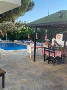 a group of people sitting at a table by a pool at Unver Holiday Homes in Marmaris