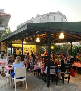 a group of people sitting at tables at a restaurant at Unver Holiday Homes in Marmaris