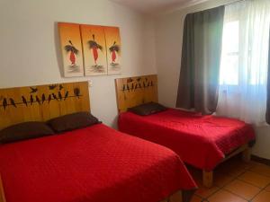 sypialnia z 2 czerwonymi łóżkami i oknem w obiekcie Cabaña Traslomita w mieście Mazamitla