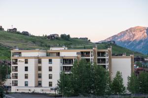 a white building with a mountain in the background at The Plaza Condominiums by Crested Butte Mountain Resort in Mount Crested Butte