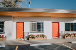 Sapphire Motel Midtown Bozeman في بوزمان: مبنى بأبواب برتقالية وزهور في موقف للسيارات