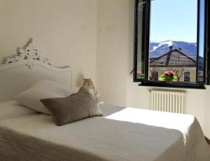 a bedroom with a white bed with a window at Hotel Villa San Fedele in San Fedele Intelvi