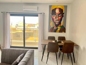 a living room with a table and a painting of a woman at 2br modern apartment in Almadies in Dakar