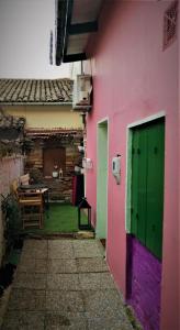 um edifício cor-de-rosa com uma porta verde e uma mesa em Loft Kapodistrias em Corfu Town
