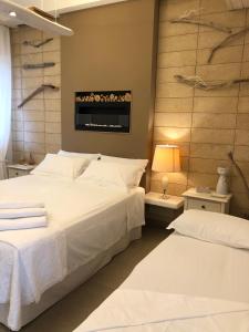 sypialnia z dwoma łóżkami i telewizorem na ścianie w obiekcie ZEROstuni suite apartment w mieście Ostuni