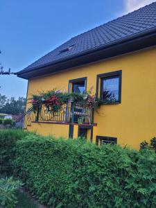 a yellow house with flowers on a balcony at Ferienwohnung Schmidt in Neu Sallenthin
