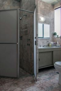 a bathroom with a shower with a toilet and a sink at Casa las Maravillas, hermosos jardines y alberca in Cuernavaca