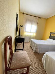 a hotel room with two beds and a chair and a desk at Hostal El Botero in Monreal del Campo