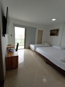 1 dormitorio con 2 camas, escritorio y TV en Hotel Palermo Sincelejo en Sincelejo