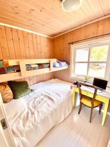 a bedroom with a bed and a desk with a laptop at Kunstnerhytte med panoramautsikt på Furuholmen in Sarpsborg