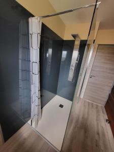 a glass shower in a room with a wooden floor at La maison du cœur in Saint-Moreil
