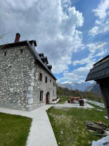 a stone building with a patio and a grass yard at Guest House Rrashkadoli in Theth