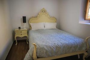 Schlafzimmer mit einem Bett mit einem goldenen Kopfteil und einem Tisch in der Unterkunft Primor Serra AL in Covilhã