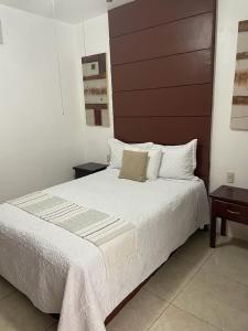 um quarto com uma cama grande e uma cabeceira castanha em Hotel Real Villa em Villa Corona
