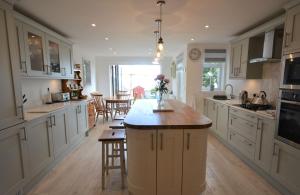 Jan Dee Cottage في فنتنور: مطبخ مع دواليب بيضاء وجزيرة مركزية مع طاولة