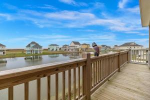 a cat sitting on a wooden deck looking at the water at Born To Beach home in Crystal Beach