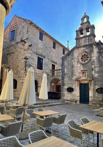 an outdoor cafe with tables and umbrellas in front of a building at Apartments Cvitanović Korčula in Korčula