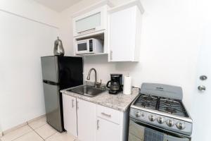 a small kitchen with a stove and a refrigerator at Green Studio 1 - just 7 min drive to the beach in Rincon