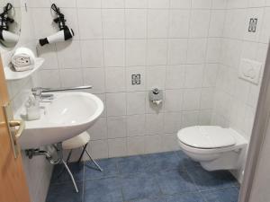 a white bathroom with a toilet and a sink at Ferienhaus Baltrumkieker Mitte in Neßmersiel