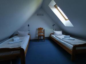 2 camas en una habitación con ventana y silla en Ferienhaus Baltrumkieker Mitte en Neßmersiel